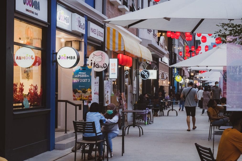 illuminated storefronts on the sidewalk