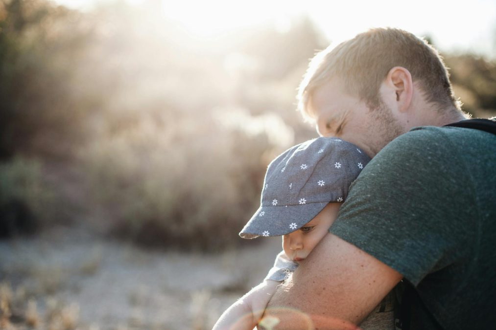 a man hugging his baby on a sunny afternoon